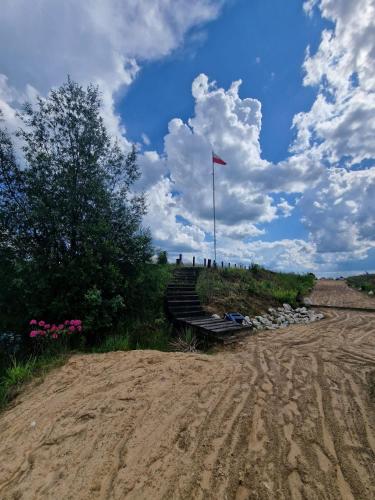 a bench with a flag on top of a dirt road at GRETA Nowoczesny domek modułowy nad stawem in Jodłowiec