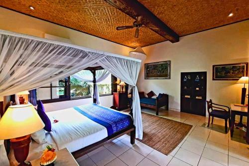 une chambre avec un lit et un bureau dans une pièce dans l'établissement Falguni 1 BR Grand Deluxe Garden View ZN241, à Ubud