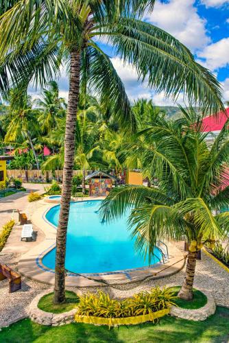 a pool with two palm trees in a resort at Lagnason's Place in Oslob