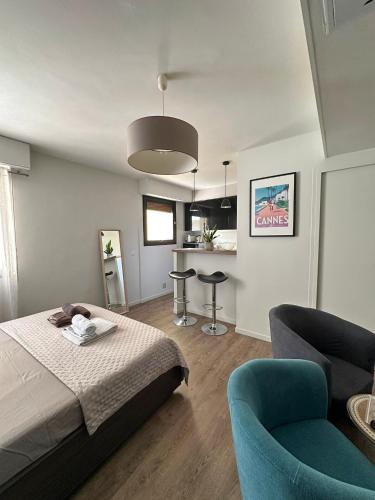 Cet appartement comprend une chambre avec un lit et deux chaises ainsi qu'une cuisine. dans l'établissement Un été à Cannes, Studio cosy à 10' de la Croisette, à Cannes