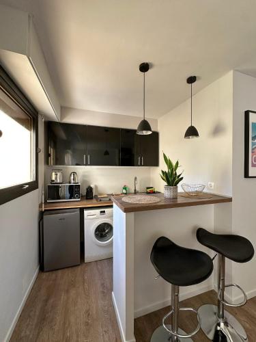 une cuisine avec un comptoir et deux tabourets de bar dans l'établissement Un été à Cannes, Studio cosy à 10' de la Croisette, à Cannes