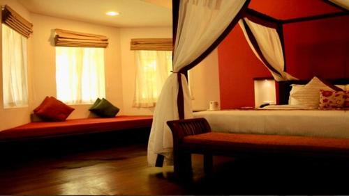a bedroom with a bed and a couch and windows at Old Lighthouse Bristow Hotel , Fort Kochi in Cochin