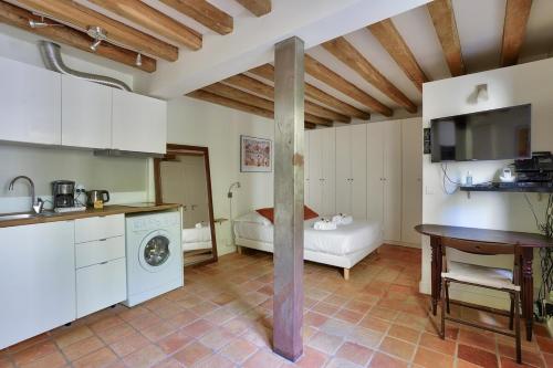 une cuisine avec des armoires blanches et une table dans une pièce dans l'établissement 3min Notre Dame de Paris | Studio, à Paris