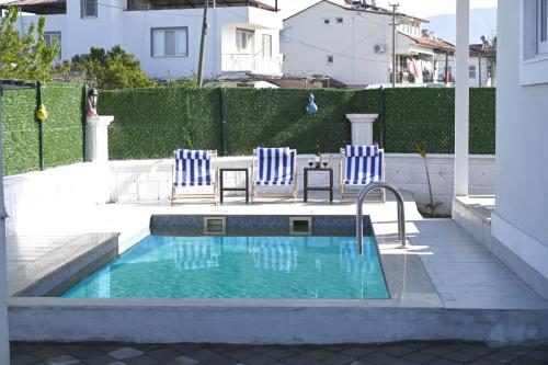 a swimming pool with two blue chairs and a table at Lavender Villas in Dalaman