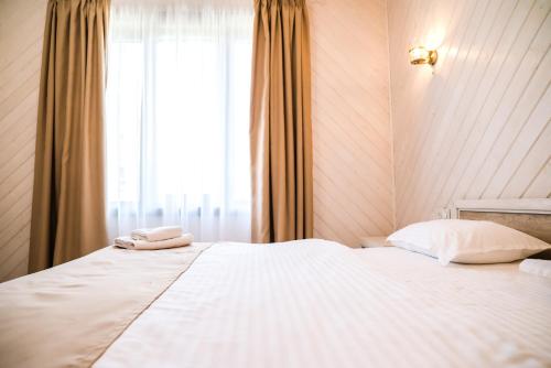 a bedroom with a large white bed with a window at Oasis Karpat in Polyana