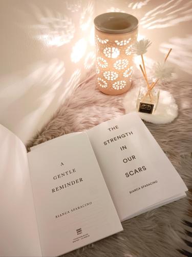 two books on a table with a candle and a vase at Hope Residences by SoCaRi in Trece Martires