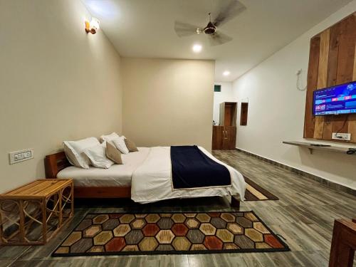 a bedroom with a bed and a flat screen tv at Grand Narmada Jungle Homestay Resort-Bandhavgarh in Tāla