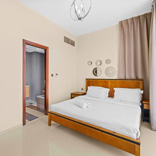 a bedroom with a large bed with white sheets at Modern 3-Bedroom Villa in Damac Hills 2 in ‘Ūd al Bayḑāʼ