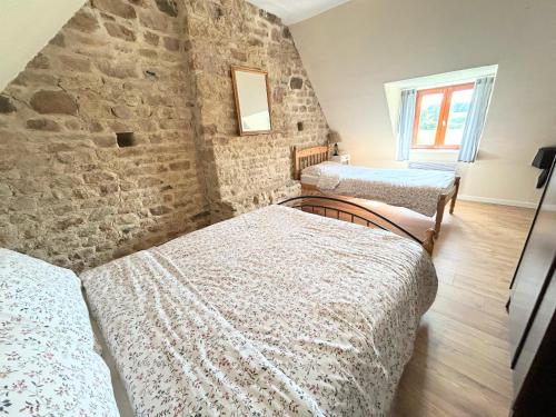 - une chambre avec 3 lits et un mur en pierre dans l'établissement Daisy Cottage with seasonal Swimming Pool, à Le Mesnil-Gilbert