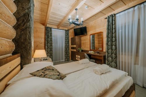 a bedroom with two beds and a desk and a television at Gordonówka Grand- blisko basenów termalnych Rezerwuj już dziś- nie przegap okazji! in Szaflary