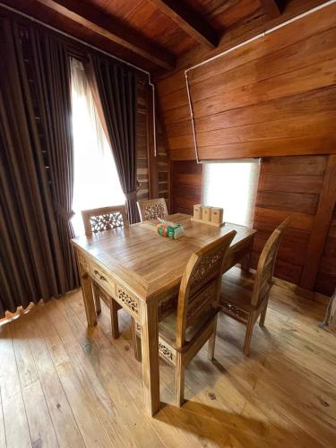 a wooden dining table and chairs in a room with wooden walls at Griya Keboen Dieng in Dieng