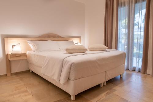 a bedroom with a white bed with a large window at MARISTESI in Siniscola