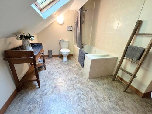 La salle de bains mansardée est pourvue de toilettes et d'un lavabo. dans l'établissement Rose Cottage with seasonal Swimming Pool, à Le Mesnil-Gilbert