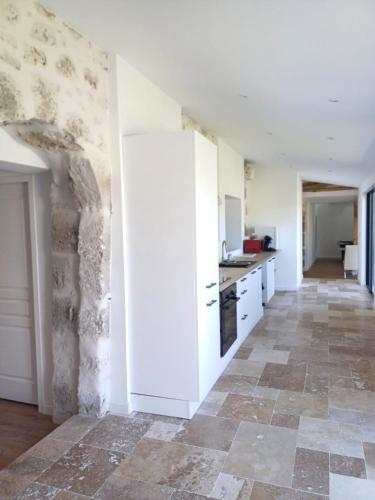une cuisine avec des armoires blanches et un sol carrelé dans l'établissement maison avec jardin 4 pers, 2 lits, billard, wifi, clim, à Foulayronnes