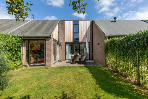 an extension to a brick house with a patio at Welcome in - Vakantiehuisje Nr 86, Op een vakantiepark met zwembad, ruime en zonnige tuin in Burgh Haamstede