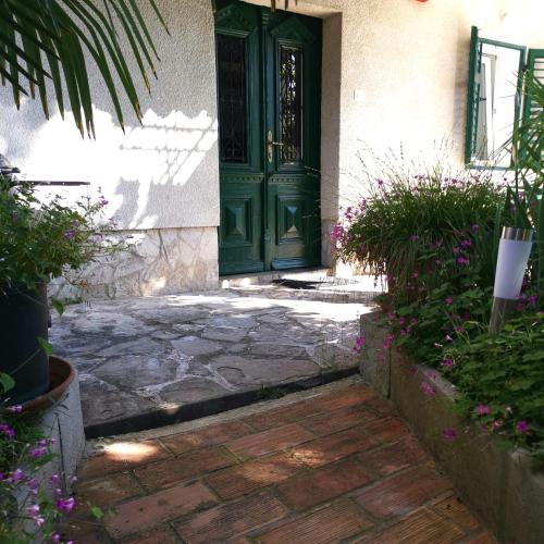 a green door on a house with flowers at Secret Garden Apartment Center Opatija with private parking space in Opatija