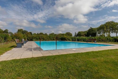 a large swimming pool in a grassy field at Welcome in - Vakantiehuisje Nr 86, Op een vakantiepark met zwembad, ruime en zonnige tuin in Burgh Haamstede