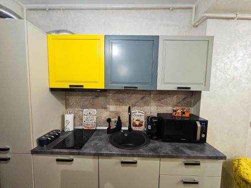 a kitchen counter with yellow cabinets and a microwave at Double View Apartment Mamaia in Mamaia