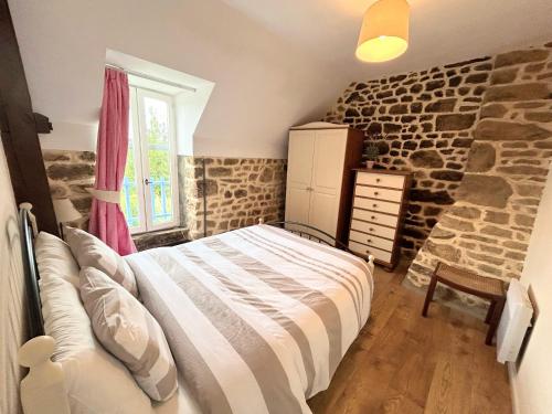 une chambre avec un lit et un mur en pierre dans l'établissement Jasmin Cottage with seasonal Swimming Pool, à Le Mesnil-Gilbert