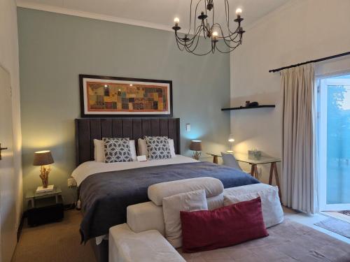 约翰内斯堡B&B on Buckingham Guest House的一间卧室，里面有一张床、一把椅子和一盏枝形吊灯