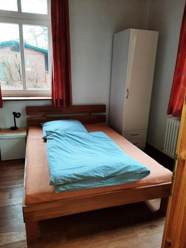 a bedroom with a bed with blue sheets and a window at Ferienwohnung Bioland-Hof Wilkens in Visselhövede
