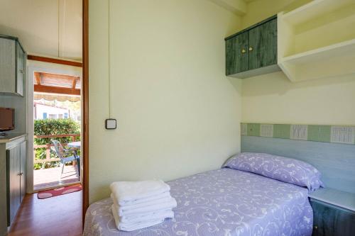 Una pequeña habitación con una cama con toallas. en Bungalow A2, en Pontevedra