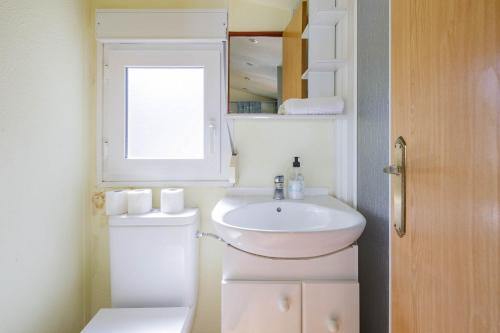 Un baño con lavabo, inodoro y ventana. en Bungalow A6, en Pontevedra