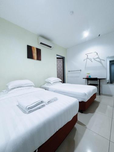 two beds in a hotel room with white sheets at Asia Green Hotel in Sungai Besar