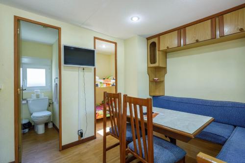 Una sala de estar con una mesa y un sofá azul. en Bungalow B1, en Pontevedra