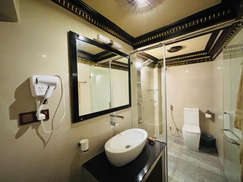 a bathroom with a sink and a mirror and a shower at Yuki Grand Hotel in Athurugiriya