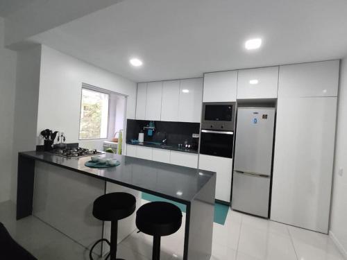 a kitchen with a counter with stools and a refrigerator at Cantinho d sossego -Two bedrooms apartment in Mindelo