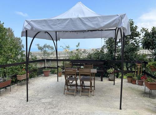 un tavolo e delle sedie sotto un ombrellone bianco di Casetta a Cavarretta a SantʼAgata di Militello