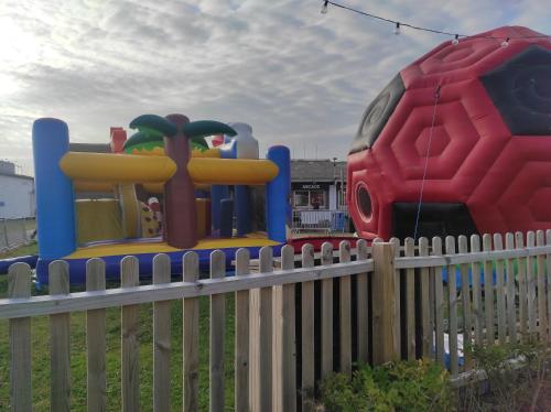 a fence with a playground equipment in a yard at 200 Breakaway Chalet in Scratby