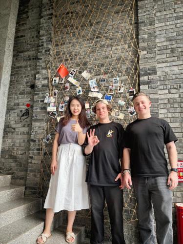 a group of three people standing in front of a wall at Riverside International Youth Hostel阅江老院青年旅舍 in Chongqing