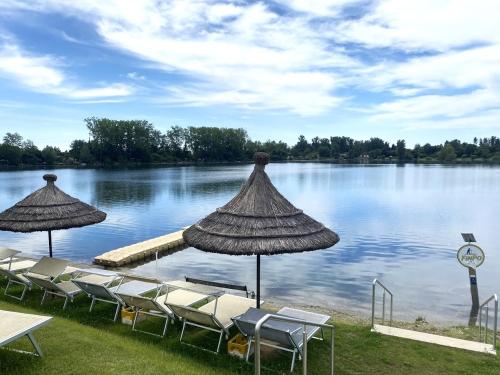 a group of chairs and umbrellas next to a lake at Ferienwohnungen Karin am Seggauberg in Leibnitz