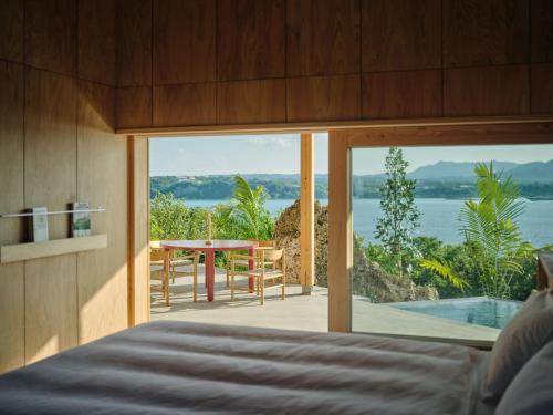 a bedroom with a bed and a view of the ocean at YAWN YARD Kouri Island in Kouri