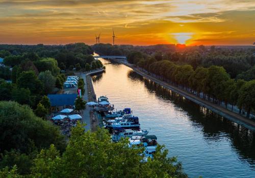 a group of boats docked in a river at sunset at De Brugdraaier - The Bridge Turner in Neerpelt