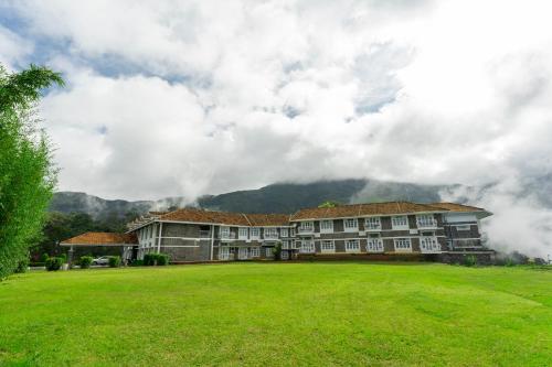 a large building with a large grass field at Le Montfort Resort in Munnar