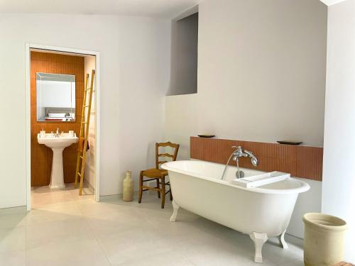une salle de bain avec une baignoire blanche et un lavabo dans l'établissement Clos Mahistre, Studio 4 étoiles, clim & piscine, à Nîmes