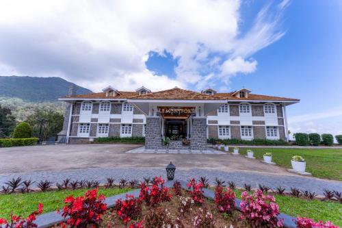 a large white building with flowers in front of it at Le Montfort Resort in Munnar