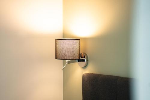a lamp attached to a wall next to a chair at Prime Park Apartment Aschaffenburg mit Terrasse in Aschaffenburg