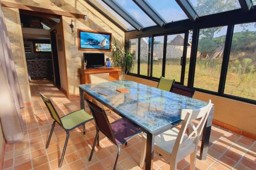une salle à manger avec une table et des chaises en verre dans l'établissement Gîte La Thébaïde 4 à 6 personnes à Missillac - Spa Jacuzzi - Loire Atlantique, à Missillac