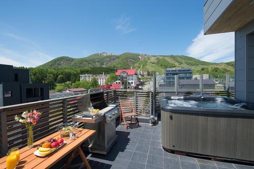 a balcony with a hot tub and a grill at The Setsumon in Kutchan