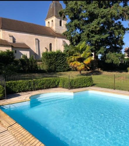 une grande piscine bleue en face d'une église dans l'établissement 10 Le Bastit, à Saint-Médard-de-Mussidan
