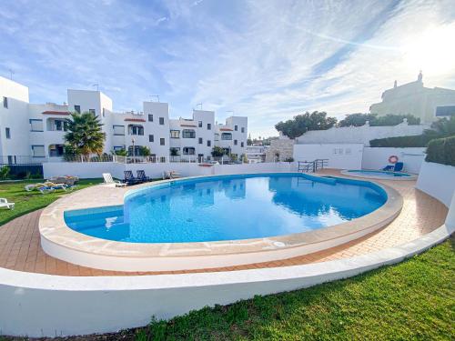 a large swimming pool in a yard with buildings in the background at Casa Joao in Carvoeiro