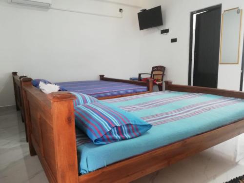 two twin beds in a bedroom with a television at David Villa in Anuradhapura