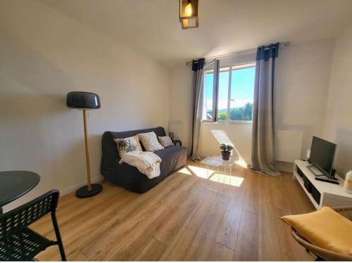 un salon avec un canapé et une grande fenêtre dans l'établissement Studio cosy à 2 pas de la mer et du centre ville d'Houlgate !, à Houlgate