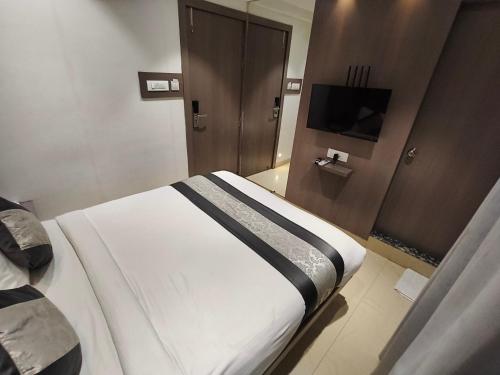 a bedroom with a large bed and a television at Hotel Pearl Residency Thane in Thane