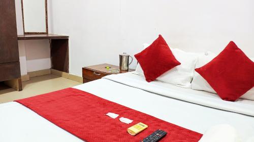 a bed with red pillows and a remote control on it at Hotel Maharaja Inn - Lajpat Nagar I in New Delhi