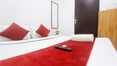 a remote control sitting on a bed with a red rug at Hotel Maharaja Inn - Lajpat Nagar I in New Delhi